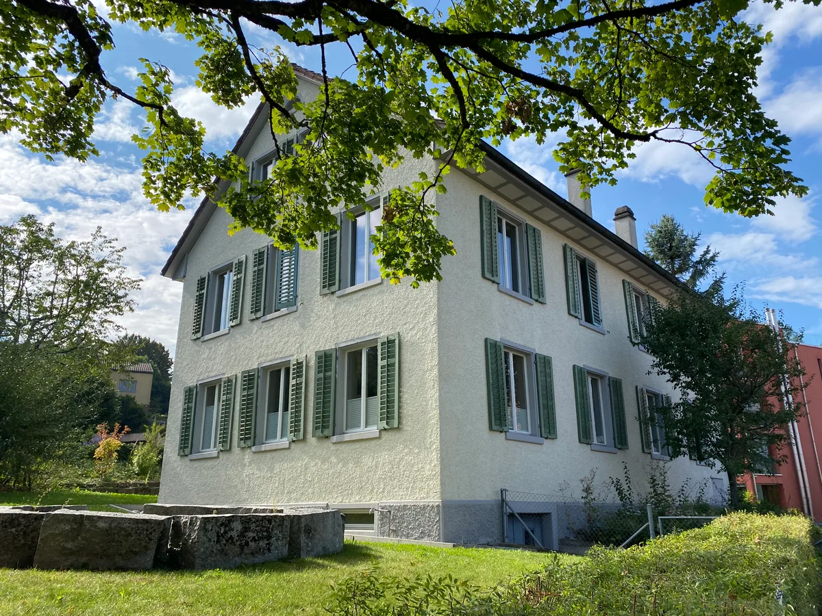 Das denkmalgeschützte «Alte Schulhaus» in Aesch soll wieder Platz für den Kindergarten bieten. (Archiv) Ein mehrstöckiges, altes, denkmalgeschütztes Gebäude ist zu sehen. Oben im Bild ist zudem ein Ast eines Baums sichtbar.